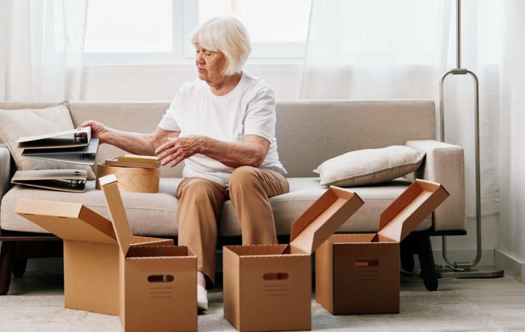 A senior packs some sentimental items into boxes while preparing to move into an assisted living community.